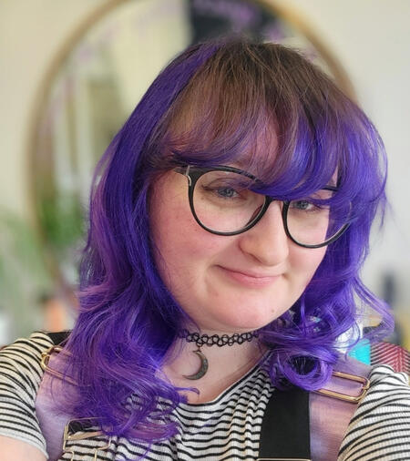 A selfie of Jessica, who has purple hair and black rimmed glasses.